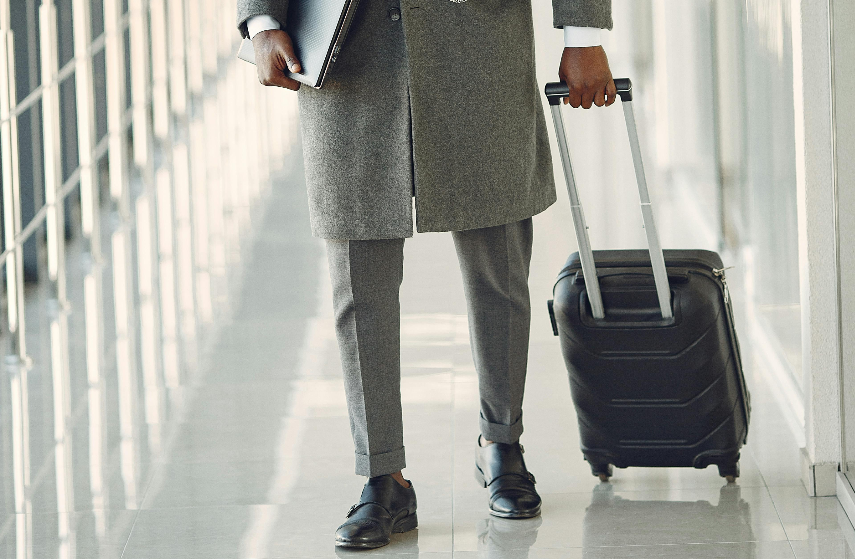 A professional on a business trip, with a case and a laptop in the airport corridor.